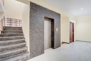 A modern interior with a marble staircase, a door, and a tiled floor. - Classic Global Tower (Mathura)