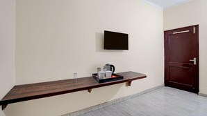 A room with a wooden bench, a flat-screen TV mounted on the wall, a door, and a tiled floor. - Classic Global Tower (Mathura)