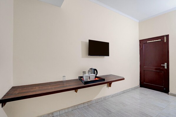 A room with a wooden bench, a flat-screen TV mounted on the wall, a door, and a tiled floor.