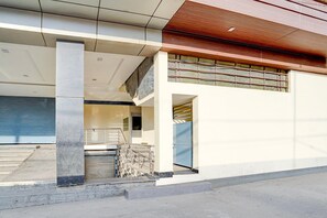 A modern building with a concrete pillar, a blue door, and a metal staircase.