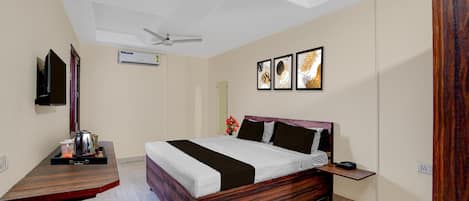 A hotel room with a bed, bedside table, a ceiling fan, an air conditioning unit, and a wall-mounted TV.