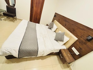 Un lit bien fait, avec une couverture matelassée, des oreillers et une tête de lit en bois.