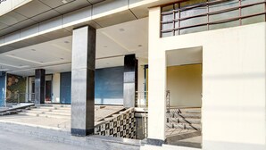 A building with a covered entrance, concrete pillars, and a staircase leading to an upper level. - Classic Global Tower (Mathura)