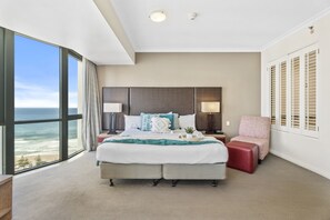 A hotel room with a large bed, two bedside tables, a chair, a view of the ocean, and a closet with shutters. - Bright Apartment Near Surfers Paradise Beach (Gold Coast)