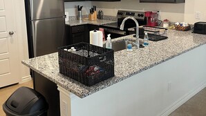 Una cucina moderna con mobili scuri, elettrodomestici in acciaio inossidabile e un piano di lavoro in granito.