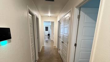 A hallway with white walls, beige carpet, and white doors.