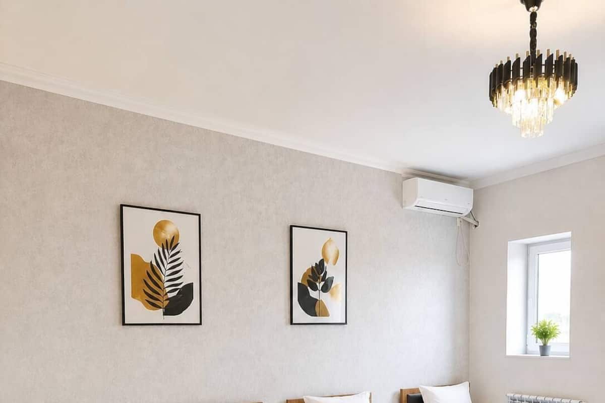 Une chambre dâhĂŽtel avec quatre lits simples, un lustre, des Ćuvres dâart aux murs et un appareil de climatisation.