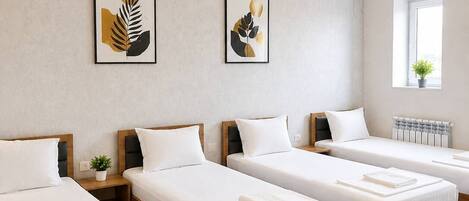 A hotel room with four single beds, a chandelier, artwork on the walls, and an air conditioning unit.