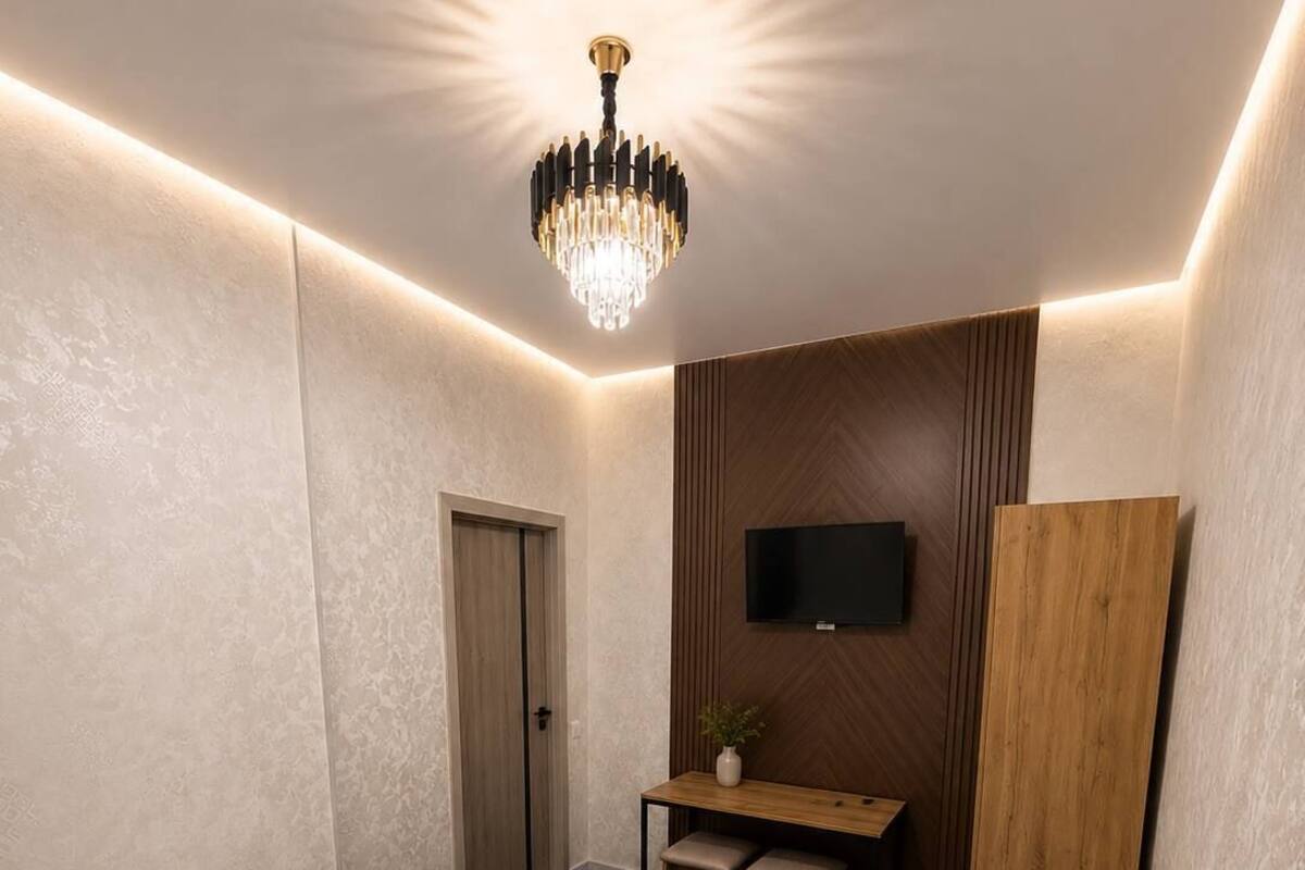 A hotel room with a bed, a desk, a chair, a TV, and a wooden panel wall.