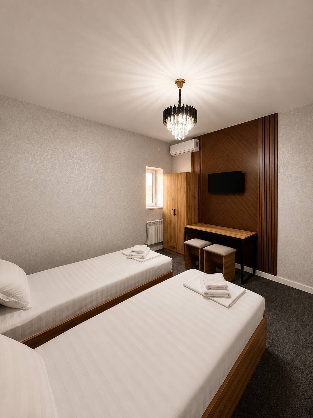 Une chambre d’hôtel avec deux lits, un bureau, une télévision et un lustre.