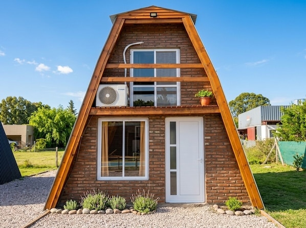 A triangular-shaped building with a brick exterior, a white door, and a window.