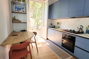 A modern kitchen with a wooden table and chairs, a built-in oven, and a view of the outdoors. - Villa Dora - Cesenatico, brand-new two-bedroom apartment with air conditioning (Cesenatico)