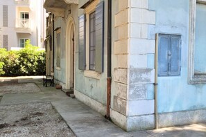 Un bâtiment doté d’une façade en pierre, de grandes fenêtres et d’une porte avec une poignée en métal.