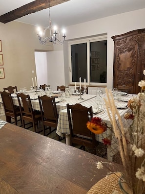 A dining room with a large wooden table set for a meal, surrounded by chairs.
