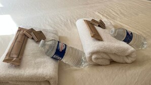 Un lit bien fait, avec du linge de lit blanc, deux oreillers jaunes et un tableau encadré accroché au mur.