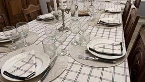 Une table à manger dressée avec des assiettes, des couverts, des verres et des bougies, entourée de chaises.