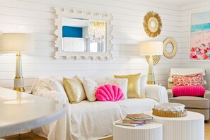Un salon décoré dans des tons de blanc, avec un canapé, deux tables d’appoint et une table basse.