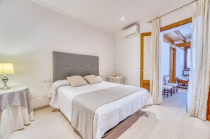 A bedroom with a bed, bedside tables, an air conditioning unit, and a view of an outdoor area. - House with pool Can Peret in Sa Pobla (Sa Pobla)