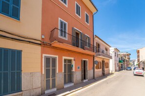 A street view with a building featuring a balcony, shutters, and a visible address number. - House with pool Can Peret in Sa Pobla (Sa Pobla)