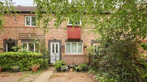 A brick residential building with a paved driveway, a black metal fence, and various potted plants. - Host & Stay | Scaife Gardens (York)
