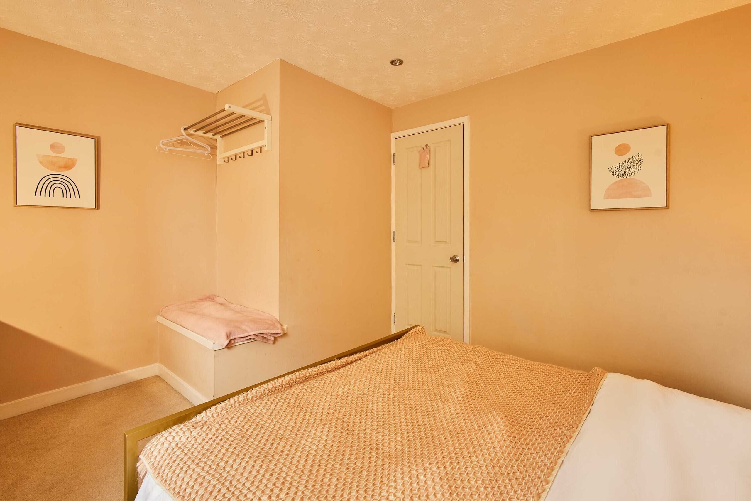 Ein Schlafzimmer mit einem Bett, einem Handtuchhalter, einer Tür und zwei gerahmten Bildern an den Wänden.