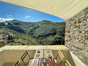 Eine Terrasse mit Tisch für zwei Personen mit Blick auf eine Berglandschaft.