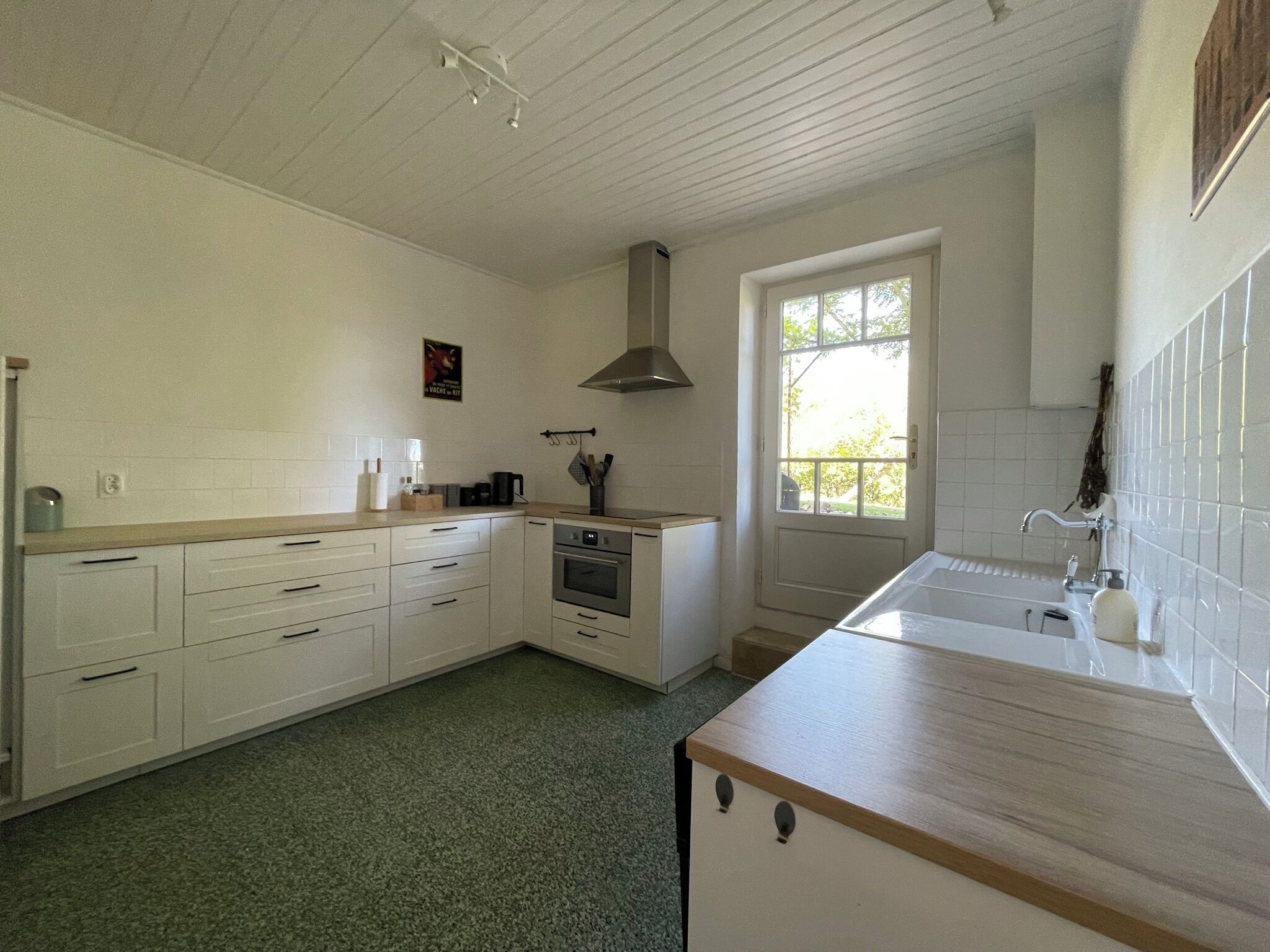A kitchen with white cabinets, a wooden countertop, a stove, and a window.