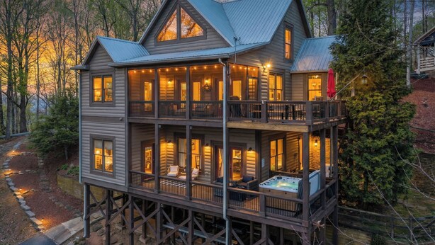Une cabane en rondins à plusieurs étages, dotée d’un balcon et d’un jacuzzi, et entourée d’arbres.