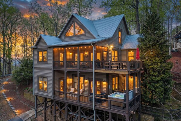 Eine mehrstöckige Blockhütte mit Balkon und Whirlpool, umgeben von Bäumen.