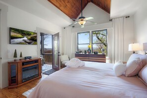 Ein Schlafzimmer mit einem großen Bett, einem Deckenventilator, einem Fenster mit Aussicht und einem Holzschrank.