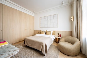 A hotel room with a bed, a round table, a chair, a wardrobe, and a wall-mounted artwork. - Neuf Cœur Paris 1-Bedroom Arts et Métiers Marais#AC (Paris)