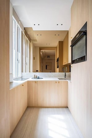 A modern kitchen with wooden cabinetry, a built-in oven, and a large window. - Neuf Cœur Paris 1-Bedroom Arts et Métiers Marais#AC (Paris)