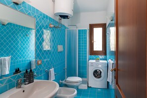 Ein Badezimmer mit Waschbecken, Bidet, Toilette und Waschmaschine.
