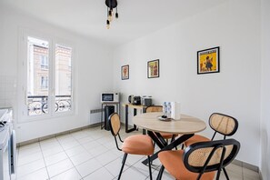 A small dining area with a round table, four chairs, a microwave, a kettle, and a poster on the wall. - Renovated Studio 2 persons Nation Bastille Paris 11 (Paris)