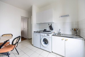 A compact kitchen with a washing machine, a sink, and a dining area with chairs. - Renovated Studio 2 persons Nation Bastille Paris 11 (Paris)