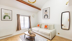 Una sala de estar moderna con un sofá, una mesa de centro, un espejo y obras de arte en las paredes.