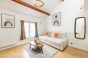 Ein modernes Wohnzimmer mit einer Couch, einem Couchtisch, einem Spiegel und Kunstwerken an den Wänden.