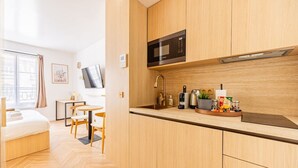 Una cocina moderna con armarios de madera, un microondas, un fregadero y un comedor con mesa y sillas.