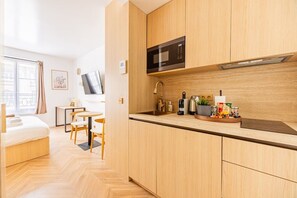 Eine moderne Küche mit Holzschränken, einer Mikrowelle, einem Spülbecken und einem Essbereich mit Tisch und Stühlen.