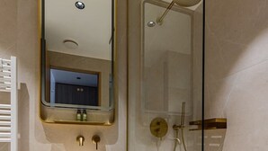 Un baño moderno con tocador de madera, un lavabo redondo, un espejo y ducha con mampara de vidrio.