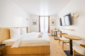 Ein Hotelzimmer mit Bett, Schreibtisch, Stuhl, Fernseher und einem Fenster mit Vorhängen.