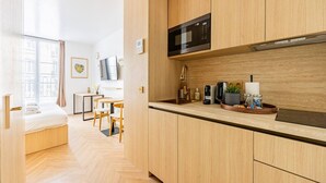 Una cocina moderna con armarios de madera, un microondas, un lavabo y una zona de comedor con mesa y sillas.