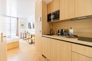 Eine moderne Küche mit Holzschränken, einer Mikrowelle, einem Spülbecken und einem Essbereich mit Tisch und Stühlen.