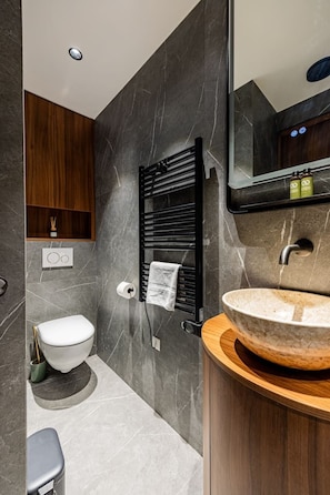 Ein modernes Badezimmer mit einem Marmorwaschbecken, einem Handtuchhalter, einer Toilette und einem Holzschrank.