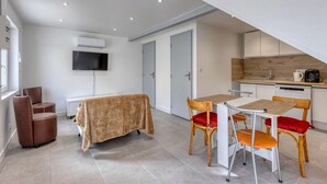 Een moderne kamer met een eettafel, stoelen, een televisie en een kitchenette.