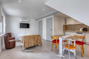 Una camera moderna con un tavolo da pranzo, sedie, TV e angolo cottura.