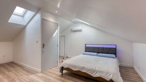 Een slaapkamer met dakraam, een bed met hoofdeinde en een houten vloer.