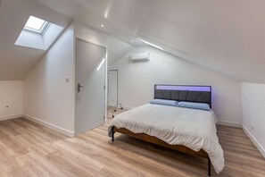 Una camera da letto con un lucernario, un letto con testiera e un pavimento in legno.