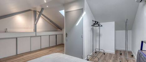 Un dormitorio moderno con techo inclinado, una cama con almohada azul, un armario y un vestidor.