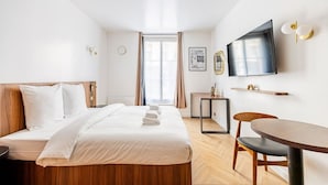 A hotel room with a bed, a desk, a chair, a TV, and a window. - 151. Luxury suite-Etienne Marcel-Châtelet-Paris 3 (Paris)